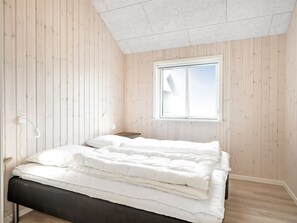 Quarto com uma cama, janela e paredes de madeira.