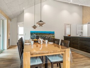 A modern dining area with a wooden table, chairs, and pendant lighting.