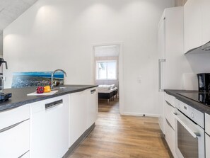 A modern kitchen with a dishwasher, a sink, and a window with a view of a beach.