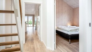 A modern interior with a wooden staircase, a hallway leading to a bedroom with a bed and a view of greenery outside. - "Merita" - 600m from the sea by Interhome (Thisted)