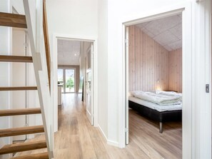 A modern interior with a wooden staircase, a hallway leading to a bedroom with a bed and a view of greenery outside. - "Merita" - 600m from the sea by Interhome (Thisted)