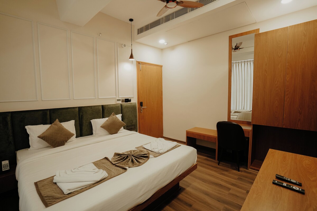 Una habitación de hotel con una cama, un escritorio, una silla, un espejo y un armario.