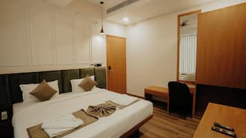 A hotel room with a bed, a desk, a chair, a mirror, and a wardrobe.