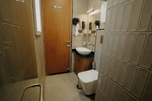 Une petite salle de bain avec une porte en bois, un lavabo blanc et des toilettes.