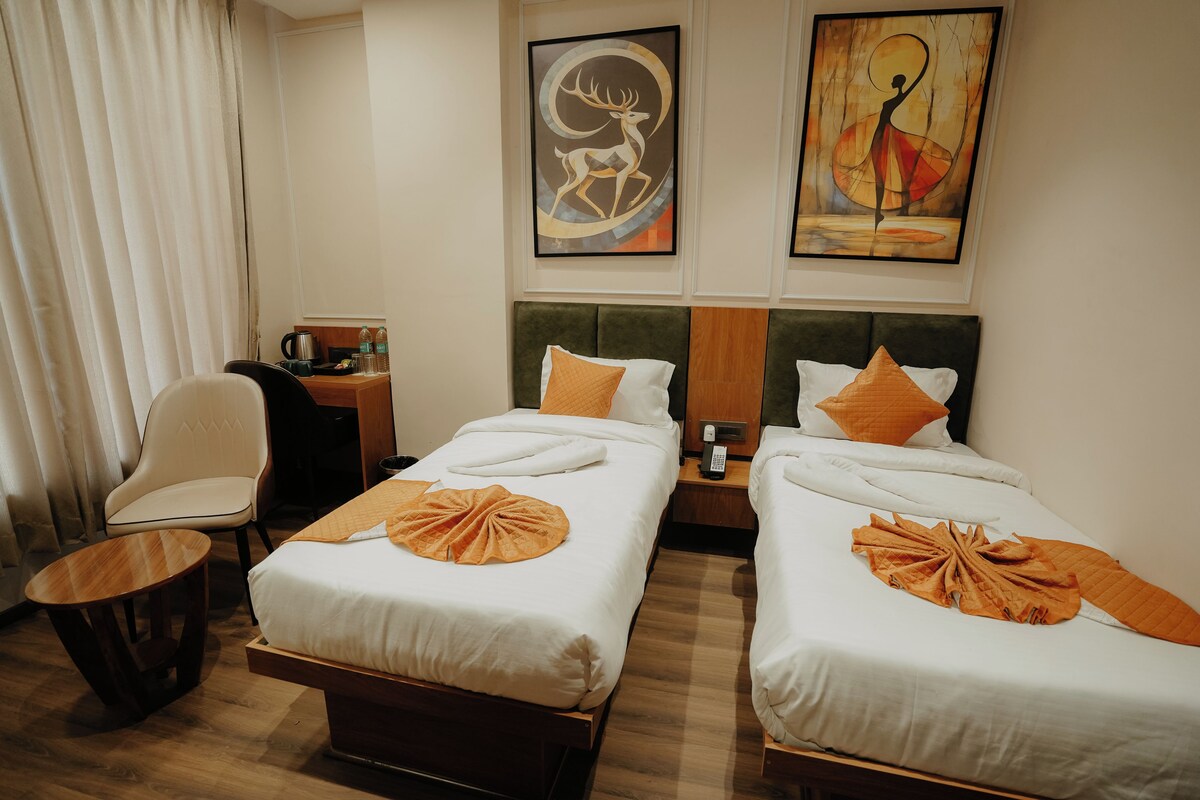 Habitación de hotel con dos camas, un escritorio, una silla y obras de arte en las paredes.