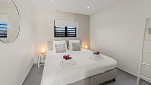 Une chambre moderne avec un grand lit, une table de chevet, un miroir et une fenêtre donnant sur un beau paysage.