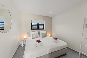 Ein modernes Schlafzimmer mit einem großen Bett, einem Nachttisch, einem Spiegel und einem Fenster mit Blick.