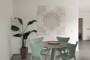 A dining area with a round table, four chairs, and a large plant. - Apartment Ayana Mambo Beach (Willemstad)