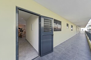 Ein Flur mit geschlossener Tür, einem Blumentopf und einem Fenster mit Jalousien.
