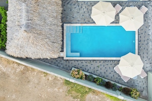A rooftop pool area with a blue pool, white umbrellas, and a thatched lounge chair. - Apartment Ayana Mambo Beach (Willemstad)