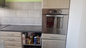 Keittiössä on mikroaaltouuni, uuni ja erilaisia elintarvikkeita työtasolla.