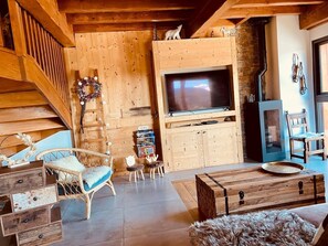 A wooden interior with a TV, wooden cabinets, a fireplace, and a staircase. - Ciméro Duplex Chalet—Luxury, Spa, Accommodates 10 Guests (Formiguères)