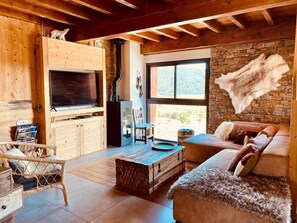 A cozy living room with a fireplace, wooden furniture, and a stone wall. - Ciméro Duplex Chalet—Luxury, Spa, Accommodates 10 Guests (Formiguères)