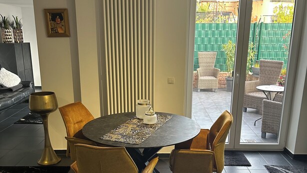 A modern living room with a round table, yellow chairs, a fireplace, and a sliding glass door leading to an outdoor patio. - Beautiful vacation rental with a terrace (Mülheim-Kärlich)