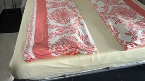 A bed with a patterned bedspread, pillows, a bedside table with a lamp, and a framed picture on the wall. - Beautiful vacation rental with a terrace (Mülheim-Kärlich)