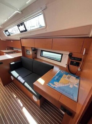 A compact interior with a sofa, a small table, and a window. - Bavaria C 42 - KIRKA (Dalmacija Marina)