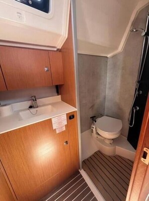 A compact bathroom with a wooden vanity, a toilet, and a shower area. - Bavaria C 42 - KIRKA (Dalmacija Marina)