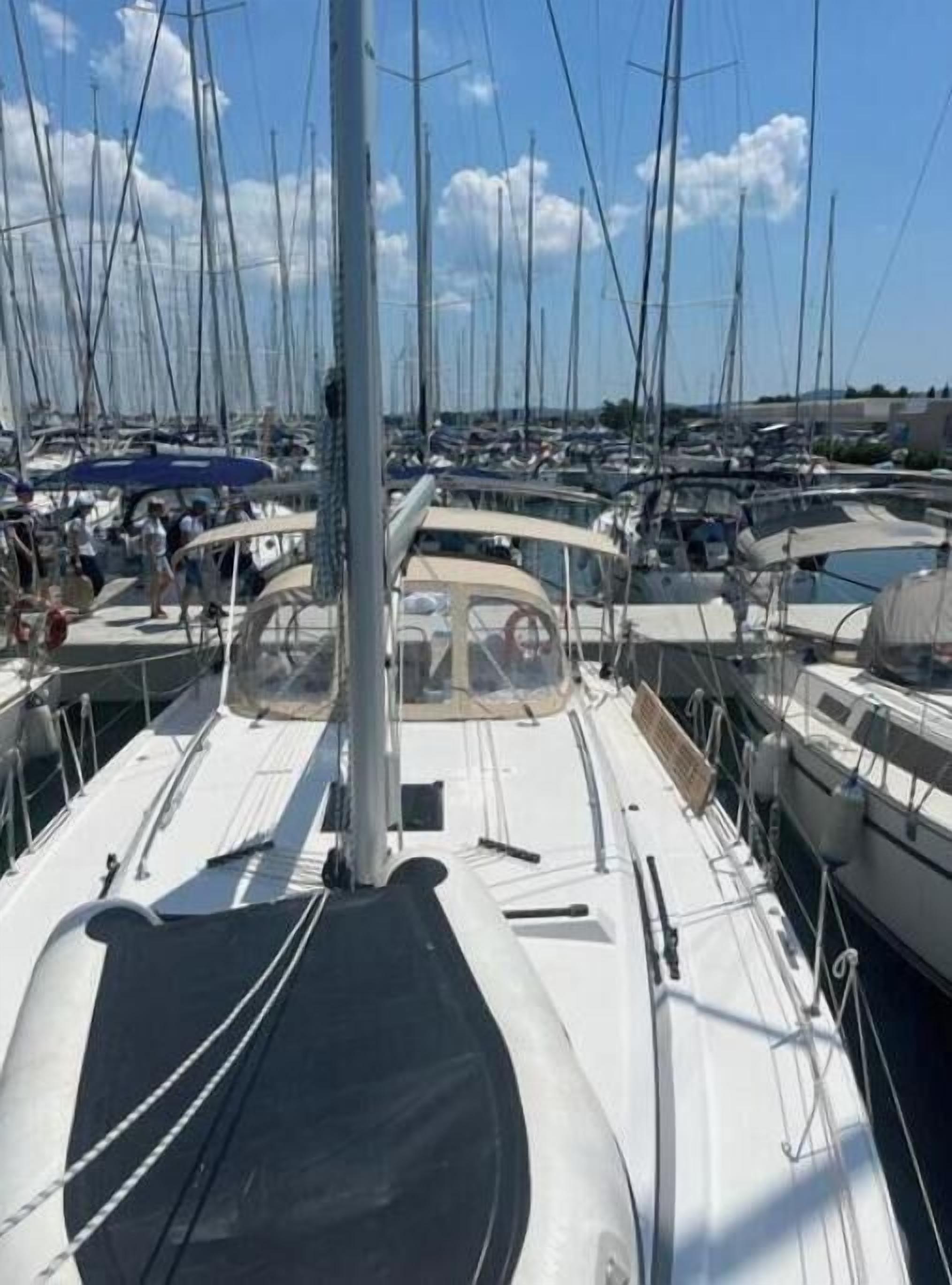 A marina with multiple boats docked, a clear sky, and a calm water surface.