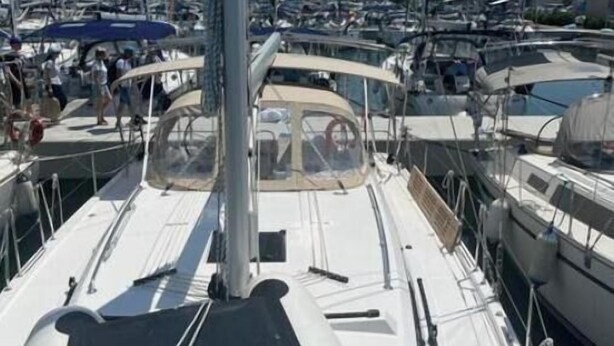 Un port de plaisance où sont amarrés de nombreux bateaux, un ciel dégagé et une surface d’eau calme.