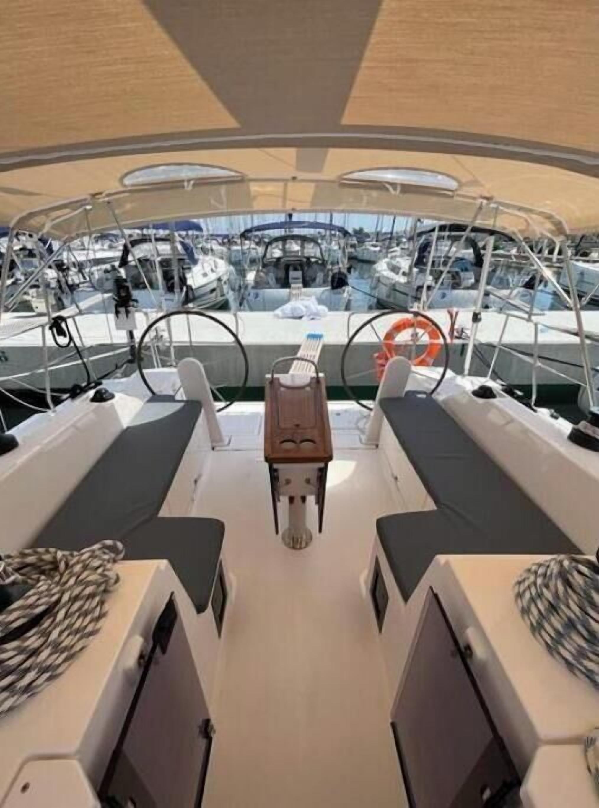 A boat deck with seating, a steering wheel, and a lifebuoy.