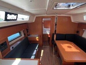 A compact interior with a seating area, a small table, and a control panel. - Bavaria C 42 - KIRKA (Dalmacija Marina)