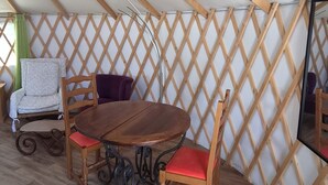 A room with a wooden ceiling, a table, and chairs. - Unique, fully equipped yurt for 2 people (Querrien)