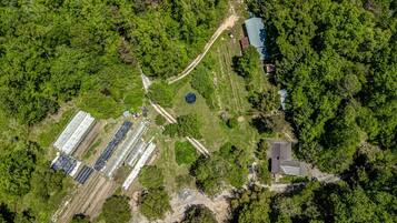 An aerial view of a property with a large greenhouse, a small building, and a pond.