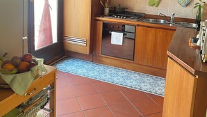 A compact kitchen with wooden cabinets, a gas stove, a microwave, and a tiled backsplash. - The Rose Apartment - Bologna (Bologna)