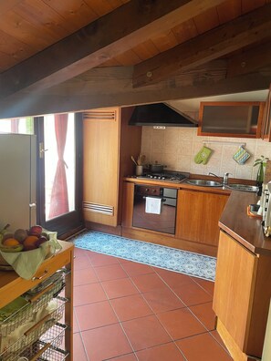 Uma cozinha compacta com armários de madeira, fogão a gás, micro-ondas e painel de azulejos.