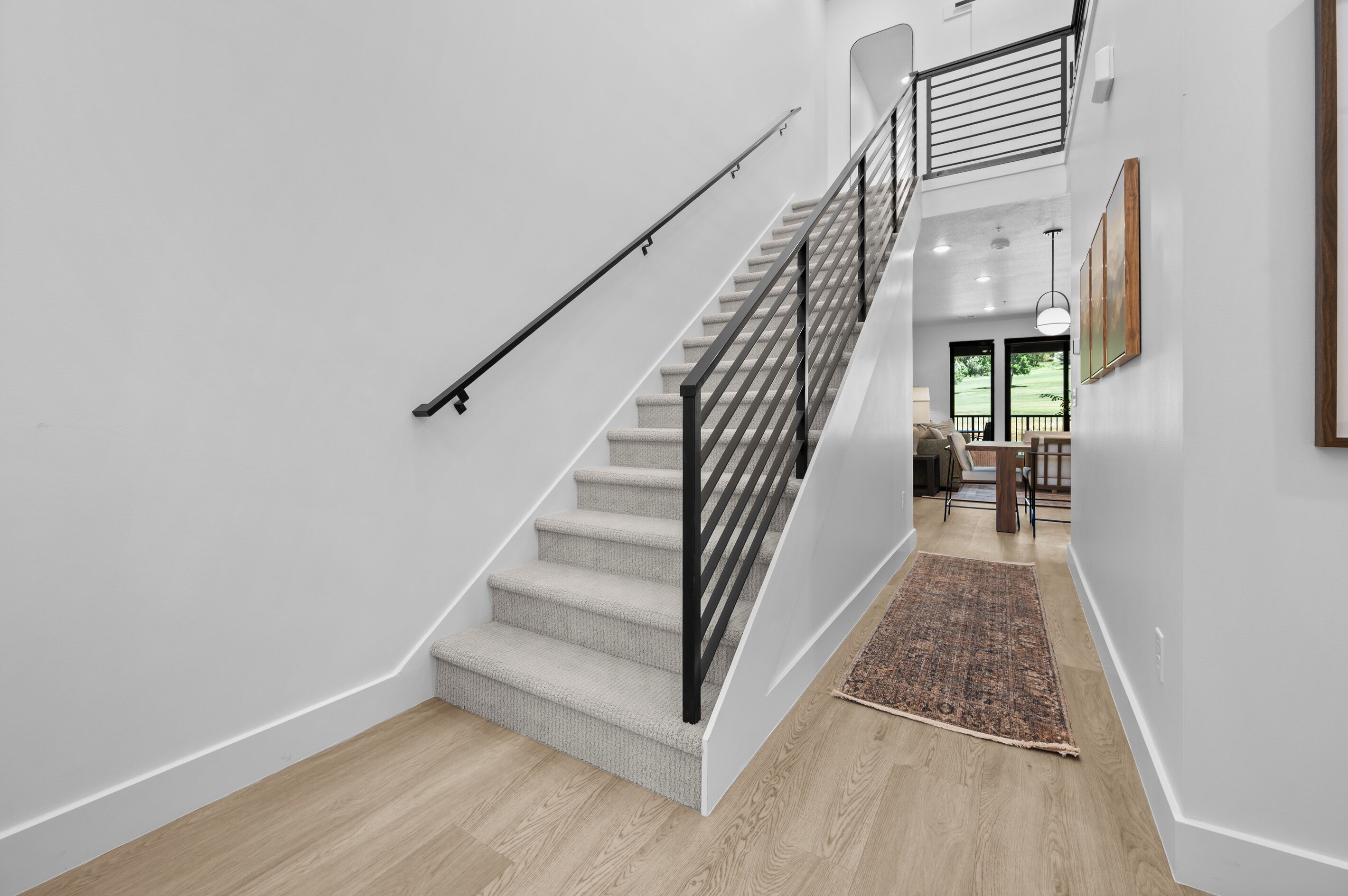 A staircase with a black railing, carpeted steps, and a wooden floor.