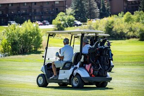Un carrito de golf en un campo verde con un edificio al fondo.