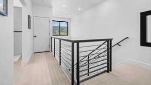 Ein modernes Interieur mit Treppe, weißen Wänden und Blick auf eine Berglandschaft.