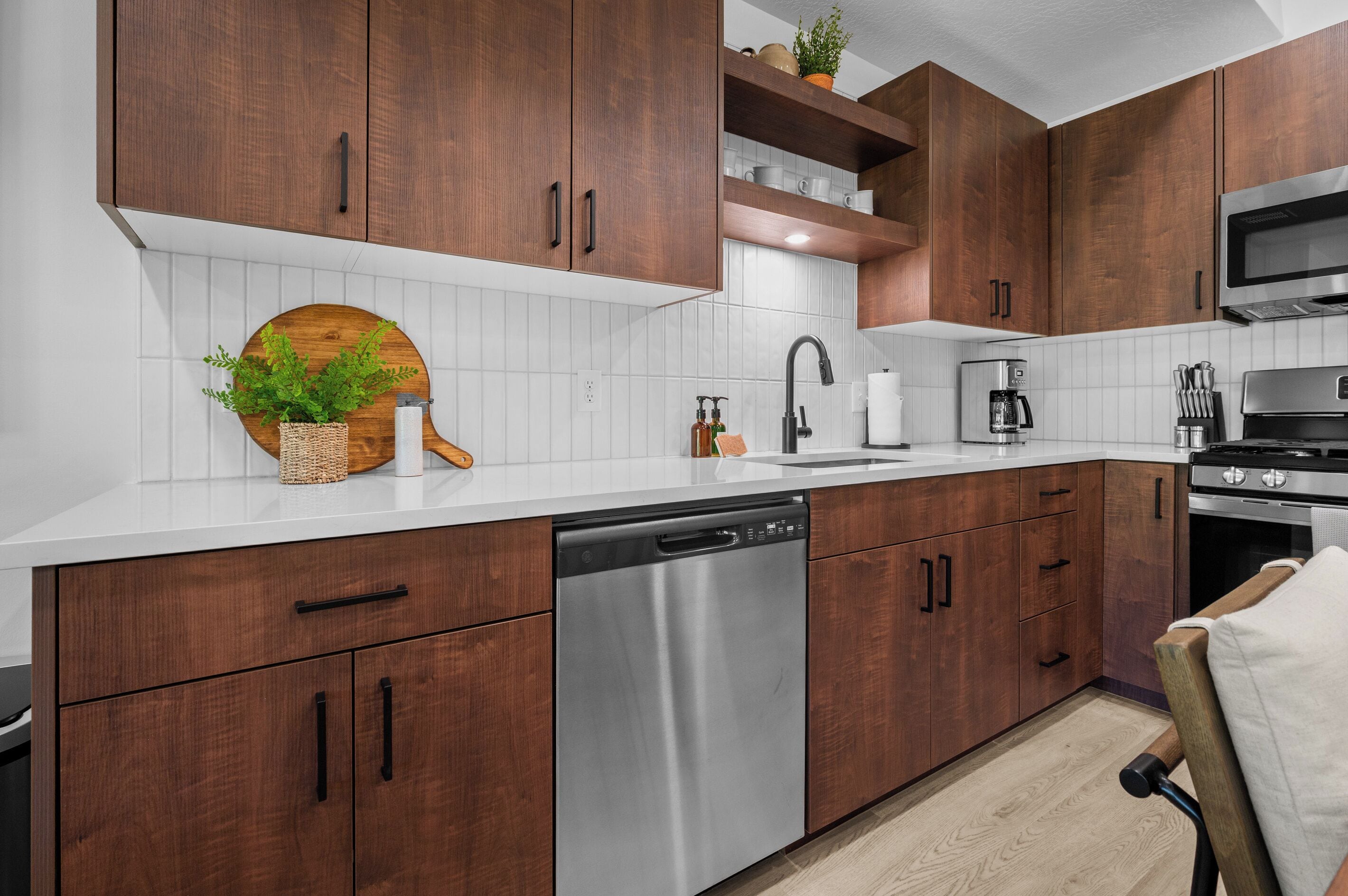 A modern kitchen with wooden cabinets, a stainless steel dishwasher, a microwave, and a coffee maker.