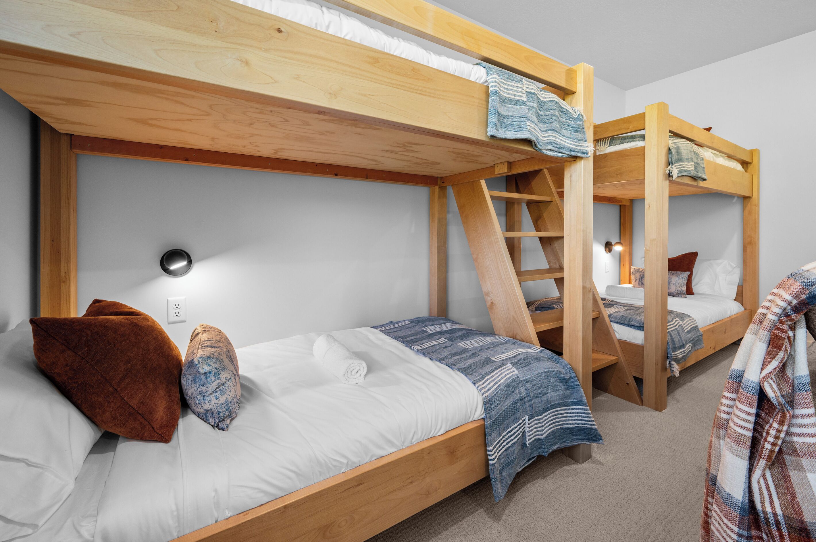 A bunk bed room with a ladder, a wall socket, and a power outlet.
