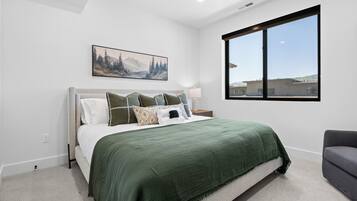 Un dormitorio con cama, ventana, un cuadro y una silla.