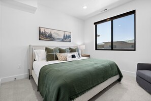 A bedroom with a bed, a window, a painting, and a chair. - Greenside Retreat Pt C207|Ski &Summer Getaway (Eden)