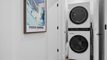 Une buanderie équipée d’un lave-linge et d’un sèche-linge à deux tambours, d’une affiche encadrée accrochée au mur et d’une porte blanche.