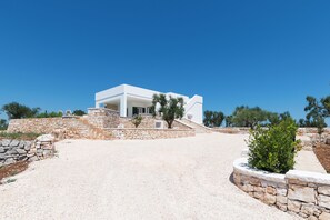 A modern white building with a stone pathway leading to the entrance. - Charming Villa with Pool by Wonderful Italy (Ostuni)
