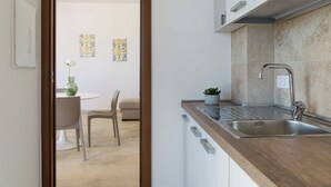 Eine moderne Küche mit Holzarbeitsplatte, Spüle aus Edelstahl und einem Essbereich mit weißem Tisch und Stühlen.