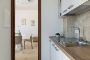A modern kitchen with a wooden countertop, stainless steel sink, and a dining area with a white table and chairs. - Charming Villa with Pool by Wonderful Italy (Ostuni)