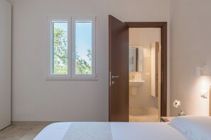 A bedroom with a bed, a window, and a door leading to a bathroom. - Charming Villa with Pool by Wonderful Italy (Ostuni)
