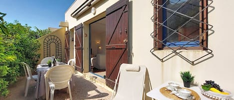 An outdoor seating area with a table, chairs, and a window with a metal grille.