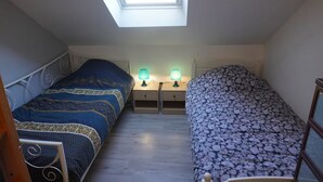 Een slaapkamer met twee bedden, een dakvenster en bedlampjes.