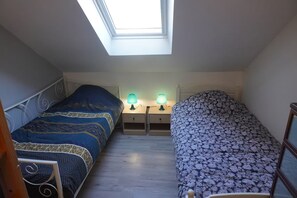 Ein Schlafzimmer mit zwei Betten, einem Oberlicht und Nachttischlampen.