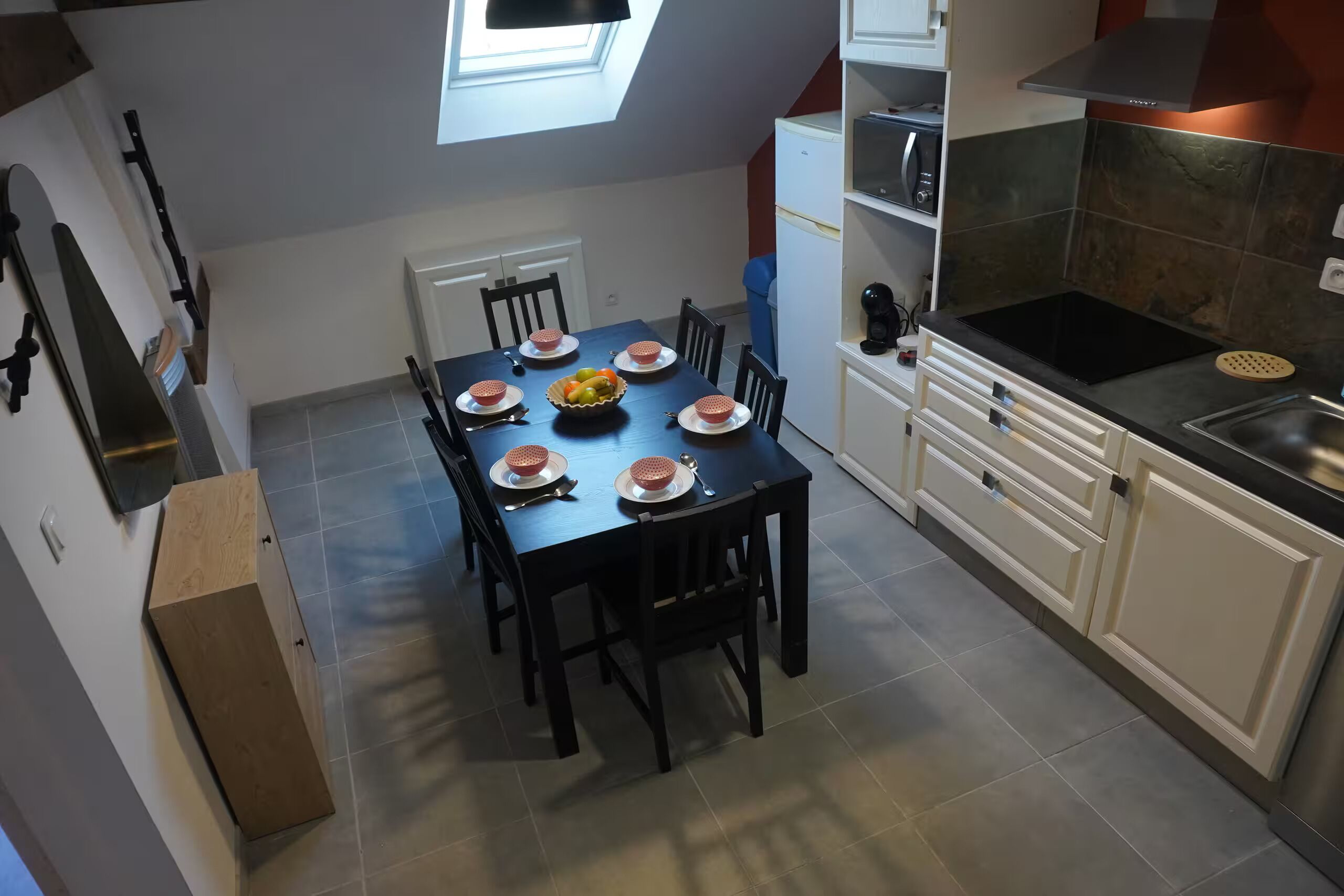 Una cuina compacta amb taula de dinar preparada per a dues persones, forn de dipòsit i nevera petita.