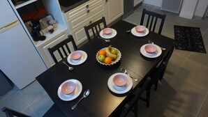 A dining table with six plates, a bowl of fruit, and a black tablecloth. - Family-friendly city apartment with 2 free private indoor parking spaces (Beuvrages)