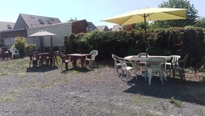 An outdoor seating area with tables and chairs, a yellow umbrella, and a building in the background.