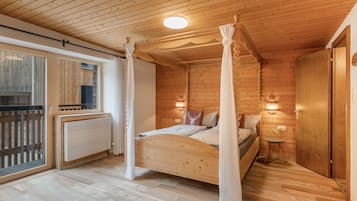 Una camera da letto in una baita di legno, con un letto a baldacchino, una finestra con persiane e una porta.