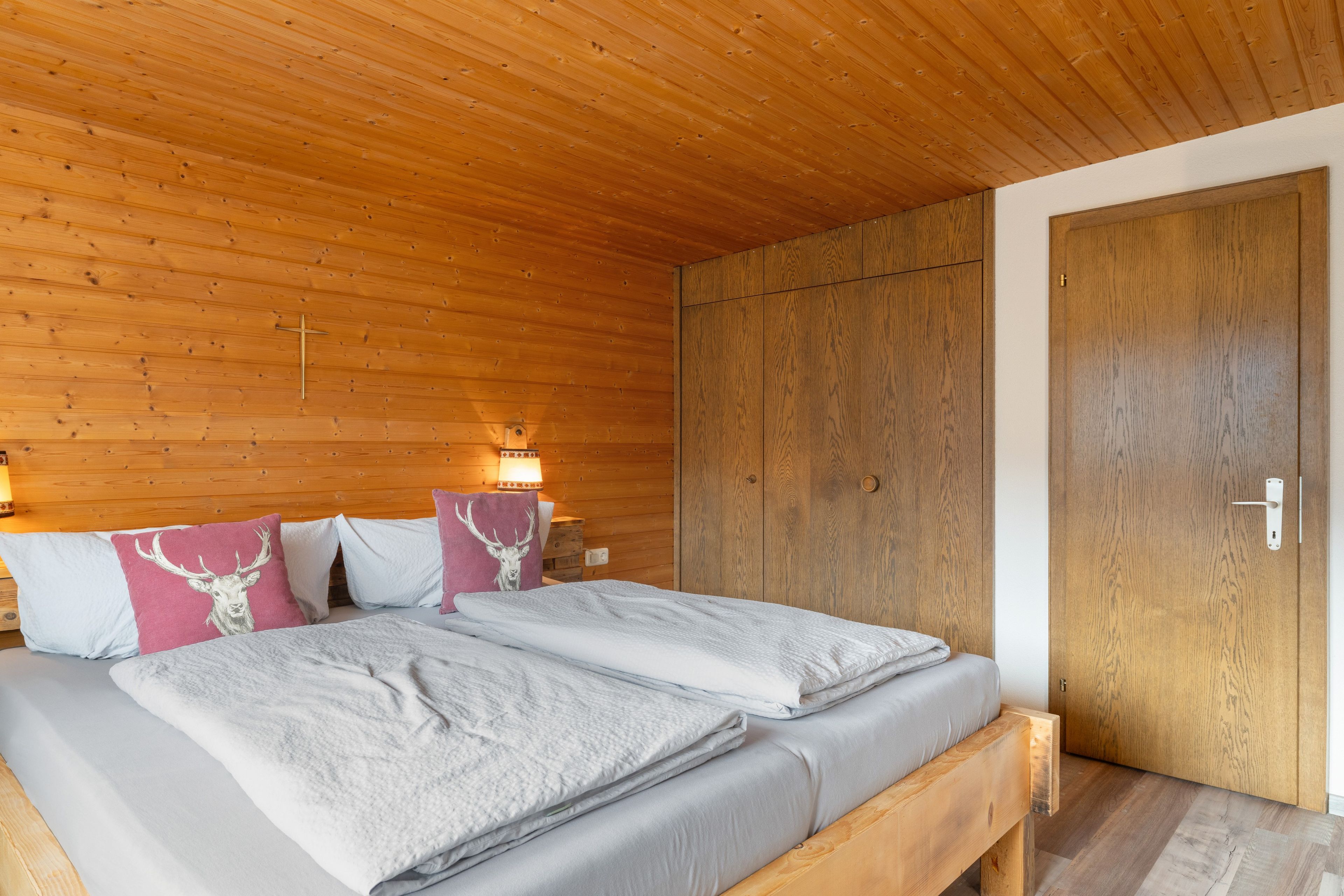 Une chambre à coucher aux murs lambrissés, avec un lit, des oreillers et une table de chevet.