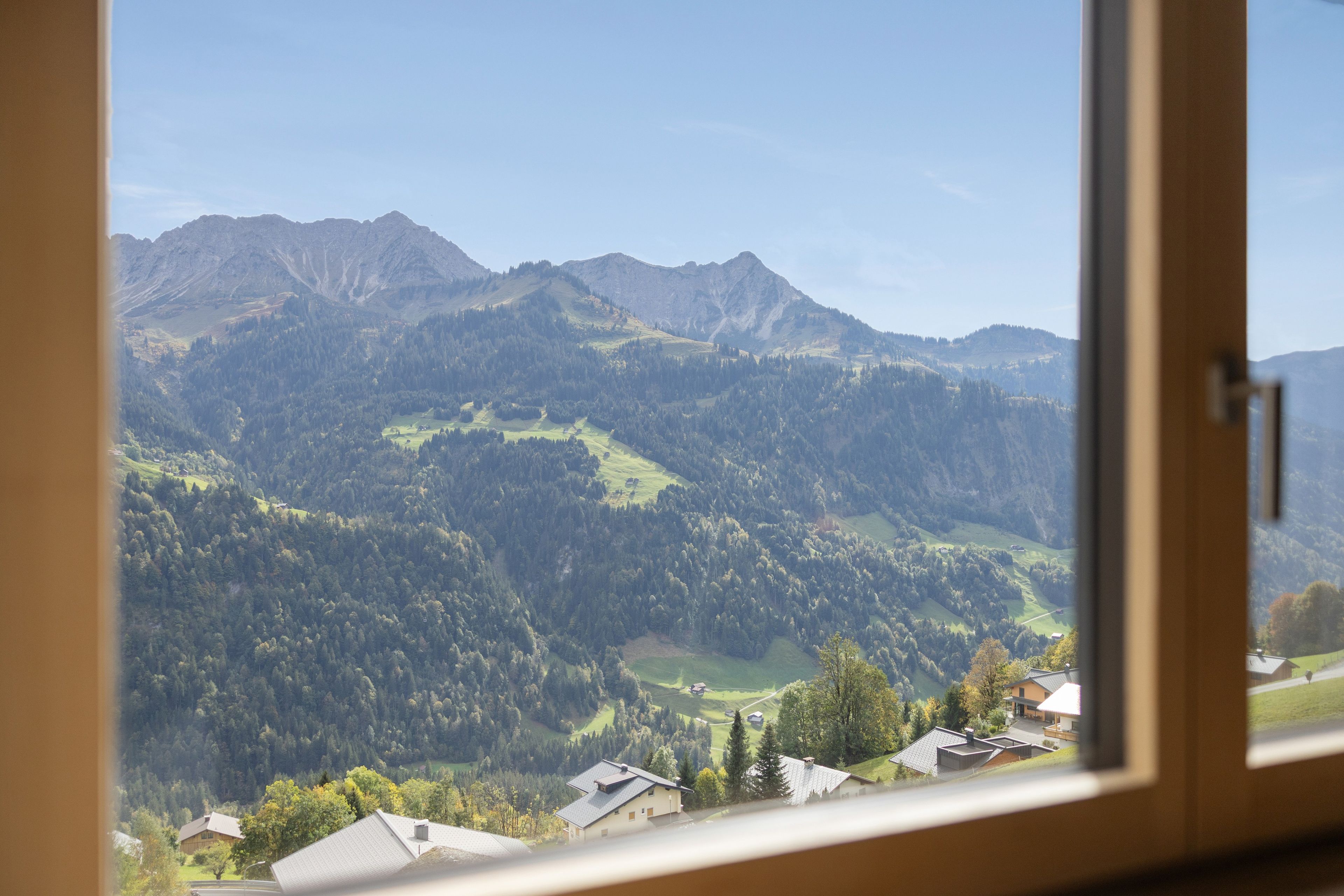Un paysage de montagne avec vue sur une zone résidentielle et une maison dotée d’un toit en pente.